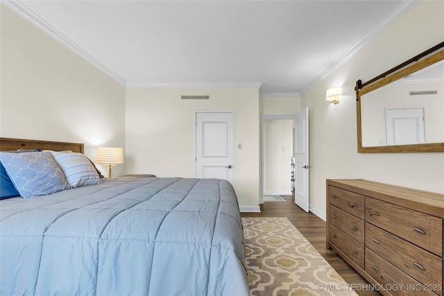 bedroom featuring dark wood-type flooring, crown molding, baseboards, and a barn door