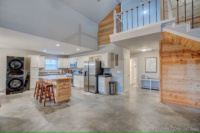 555 Williams Dr, Eufaula, OK 74432 - kitchen with stainless steel appliances, stacked washer / dryer, high vaulted ceiling, finished concrete floors, and a kitchen breakfast bar