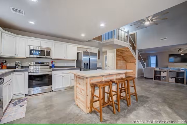 555 Williams Dr, Eufaula, OK 74432 - kitchen featuring stainless steel appliances, concrete flooring, a ceiling fan, a kitchen island, and white cabinetry