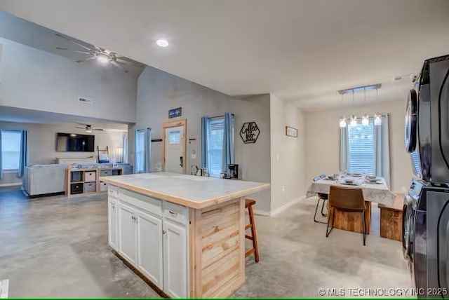 555 Williams Dr, Eufaula, OK 74432 - kitchen featuring stacked washer / dryer, open floor plan, ceiling fan, white cabinetry, and baseboards