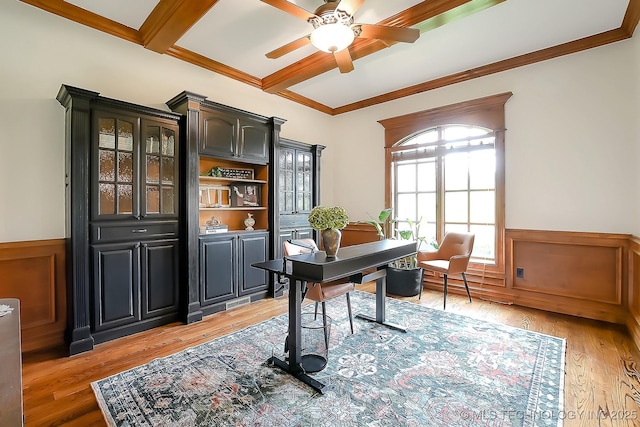 office space featuring a ceiling fan, wainscoting, light wood-style flooring, beamed ceiling, and crown molding
