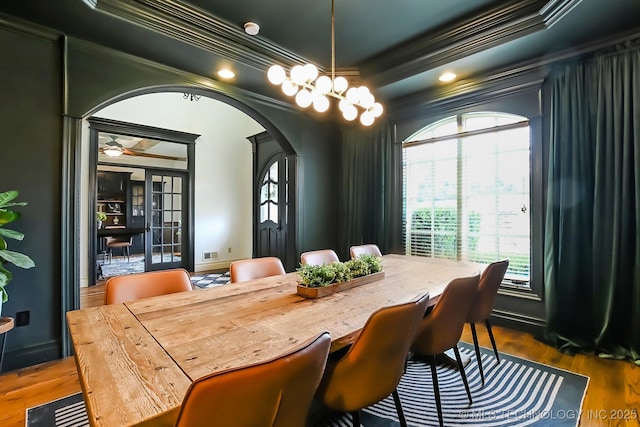 dining area with arched walkways, crown molding, plenty of natural light, wood finished floors, and recessed lighting