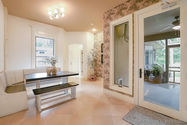 entryway with arched walkways, a ceiling fan, plenty of natural light, and light tile patterned floors