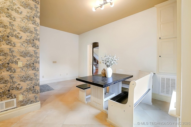 unfurnished dining area featuring arched walkways, baseboards, and light tile patterned flooring