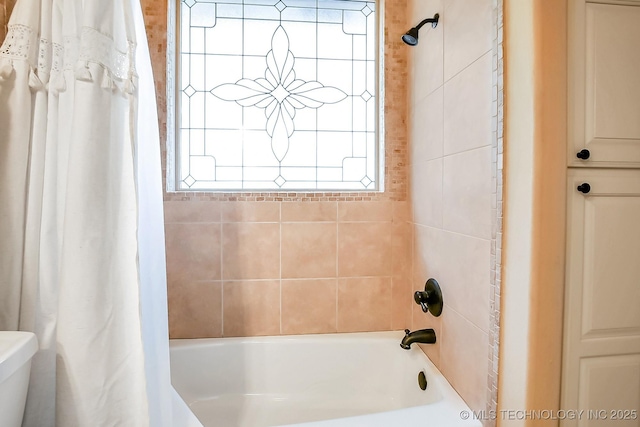 bathroom with shower / bath combo with shower curtain and toilet