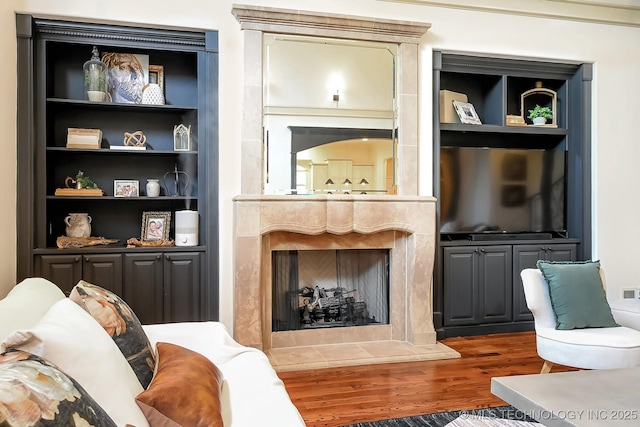 living area featuring wood finished floors, a fireplace, and built in features