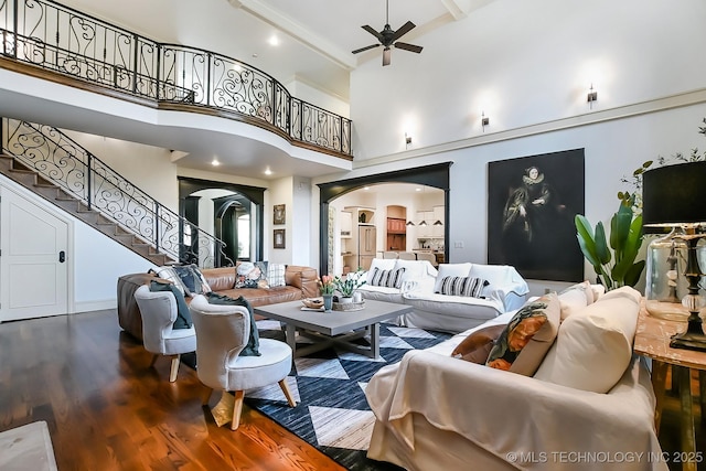 living room featuring arched walkways, ceiling fan, wood finished floors, a high ceiling, and stairs