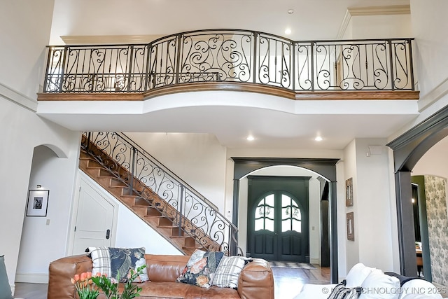 entryway with arched walkways, a high ceiling, stairway, recessed lighting, and baseboards