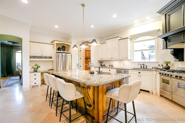 kitchen featuring appliances with stainless steel finishes, a sink, open shelves, a breakfast bar, and light stone countertops