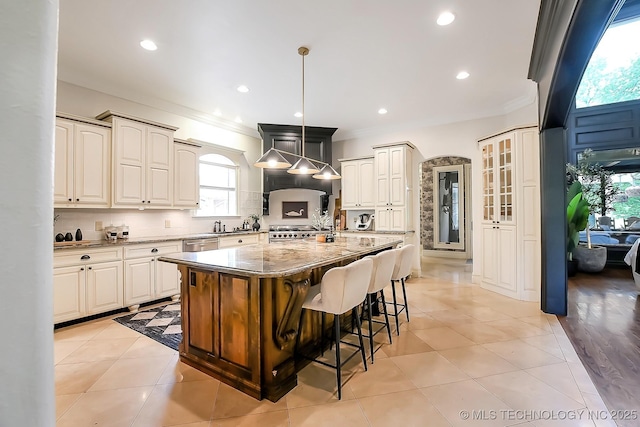 kitchen featuring light stone counters, a breakfast bar area, healthy amount of natural light, crown molding, and backsplash