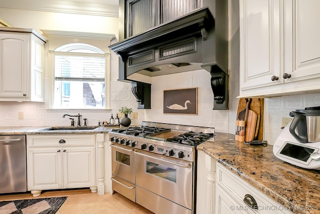 kitchen with appliances with stainless steel finishes, a sink, crown molding, light tile patterned flooring, and backsplash