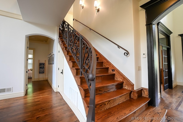 stairs featuring arched walkways, wood finished floors, and baseboards
