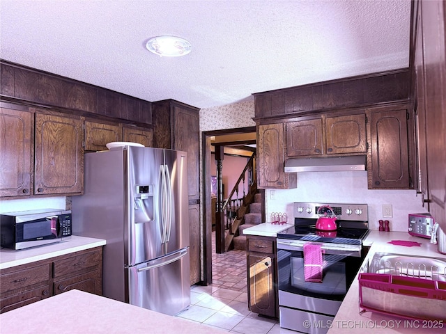 2902 Hilltop Ave, Muskogee, OK 74403 - kitchen with stainless steel appliances, under cabinet range hood, light countertops, and a textured ceiling