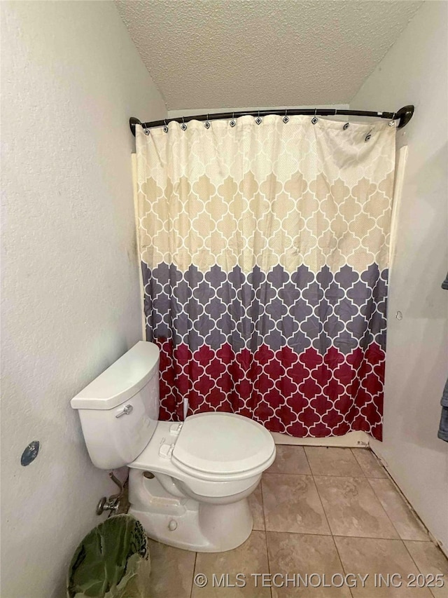 full bath featuring a textured ceiling, toilet, tile patterned flooring, and a shower with shower curtain