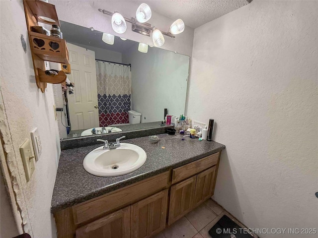 bathroom featuring a textured ceiling, a textured wall, tile patterned flooring, vanity, and toilet