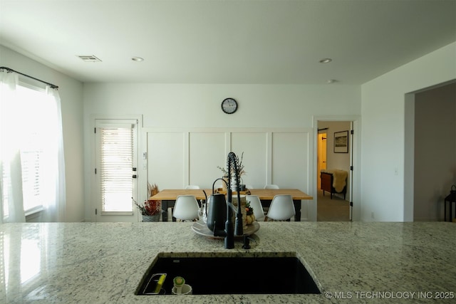 118 W 130th Pl S, Jenks, OK 74037 - kitchen with light stone counters, plenty of natural light, a sink, and a decorative wall