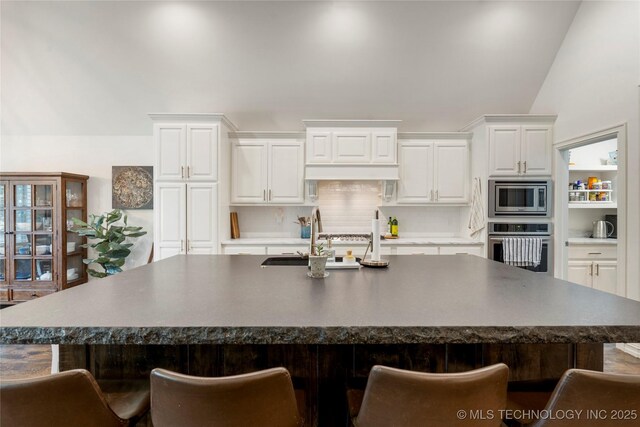 2835 E 104th St, Tulsa, OK 74137 - kitchen featuring stainless steel appliances, a sink, a kitchen breakfast bar, dark countertops, and white cabinets