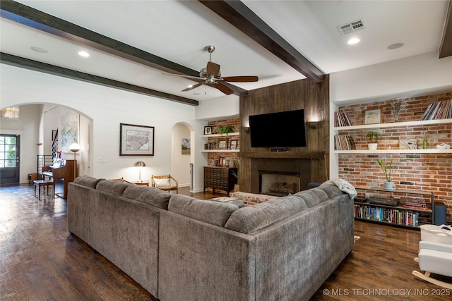 2835 E 104th St, Tulsa, OK 74137 - living room featuring arched walkways, dark wood finished floors, beamed ceiling, ceiling fan, and a fireplace