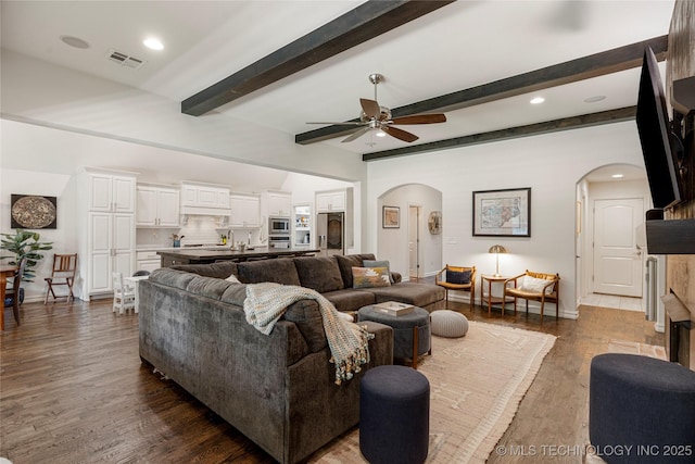 2835 E 104th St, Tulsa, OK 74137 - living room with arched walkways, a ceiling fan, dark wood-type flooring, beamed ceiling, and baseboards