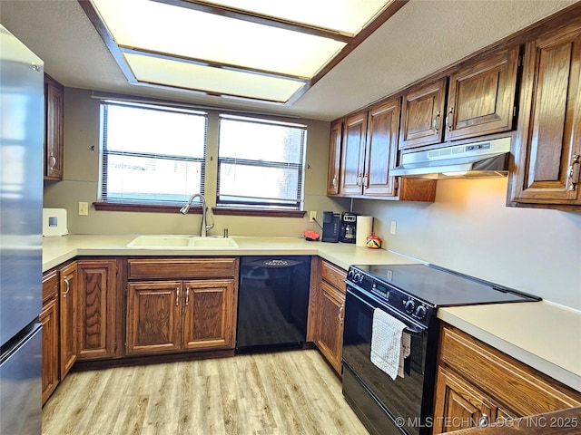 5281 Nowata Rd Unit Q101, Bartlesville, OK 74006 - kitchen featuring black appliances, under cabinet range hood, a sink, light wood-style floors, and light countertops