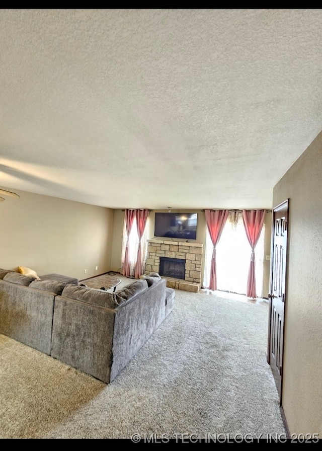 5281 Nowata Rd Unit Q101, Bartlesville, OK 74006 - living area featuring carpet floors, a stone fireplace, plenty of natural light, and a textured ceiling