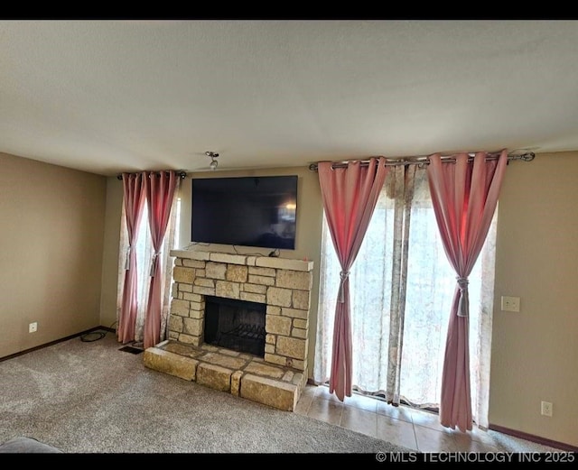 5281 Nowata Rd Unit Q101, Bartlesville, OK 74006 - unfurnished living room with a stone fireplace, baseboards, and carpet flooring