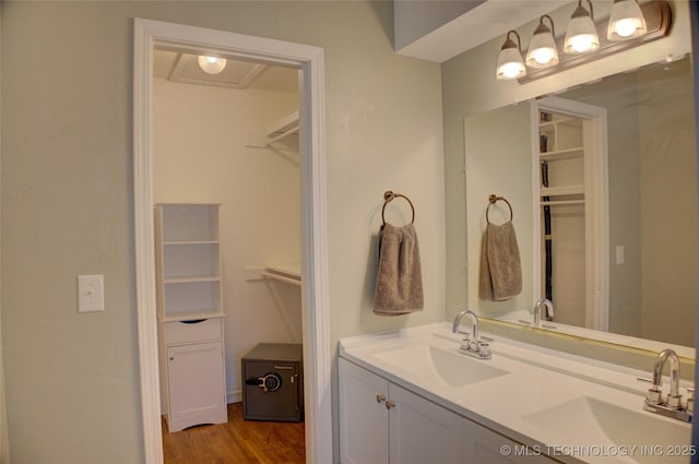 full bathroom featuring a spacious closet, double vanity, and wood finished floors