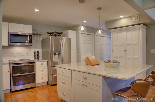 kitchen featuring appliances with stainless steel finishes, white cabinets, backsplash, light wood finished floors, and recessed lighting