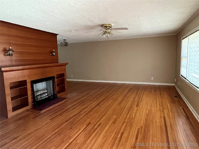 1506 E 46th Pl, Tulsa, OK 74105 - unfurnished living room featuring a ceiling fan, a textured ceiling, wood finished floors, a fireplace, and baseboards