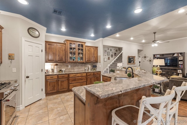 7333 S 286th E Ave, Broken Arrow, OK 74014 - kitchen with a sink, stainless steel gas range oven, brown cabinets, a breakfast bar, and ornamental molding