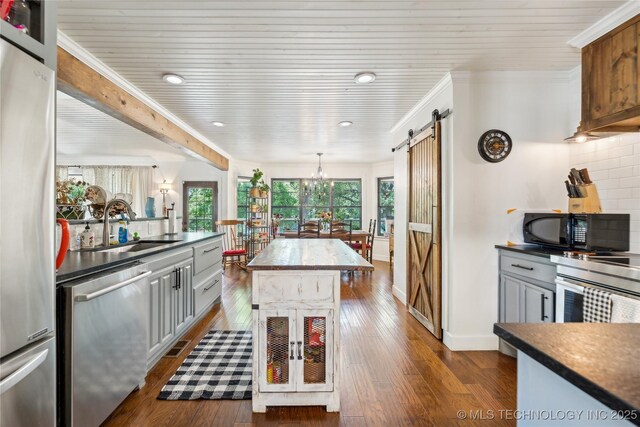 kitchen with stainless steel appliances, a barn door, a sink, dark wood-type flooring, and wooden ceiling
