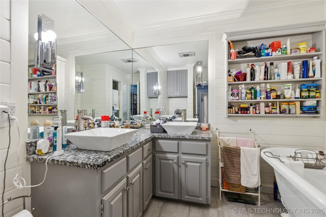 full bathroom with crown molding, double vanity, and a freestanding tub