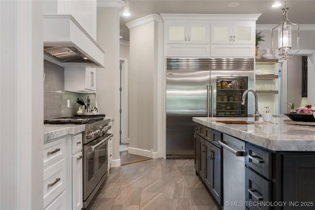 6830 E 109th St, Tulsa, OK 74133 - kitchen featuring premium appliances, custom range hood, a sink, light stone countertops, and ornamental molding