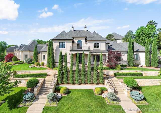 6830 E 109th St, Tulsa, OK 74133 - french country style house featuring a balcony, stucco siding, stairs, and a front lawn