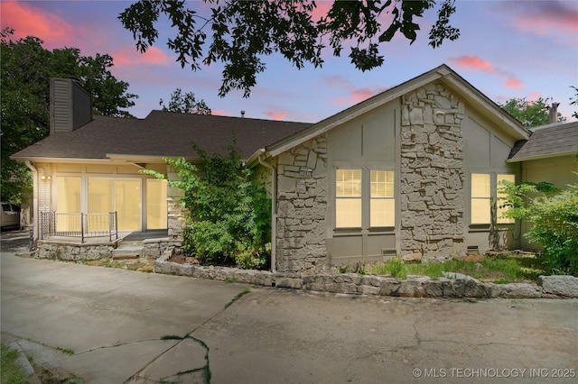 3901 E 60th Pl, Tulsa, OK 74135 - back of house at dusk with stone siding and a chimney