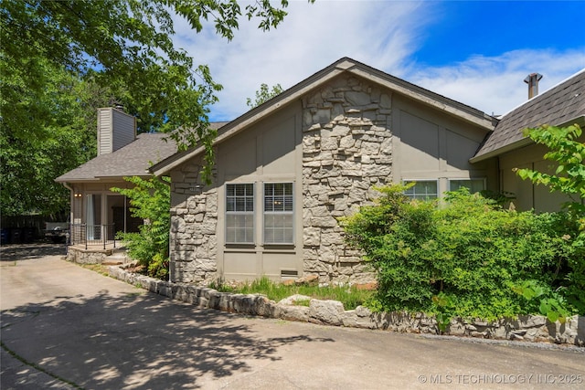 3901 E 60th Pl, Tulsa, OK 74135 - view of side of home featuring stone siding, a chimney, and a shingled roof