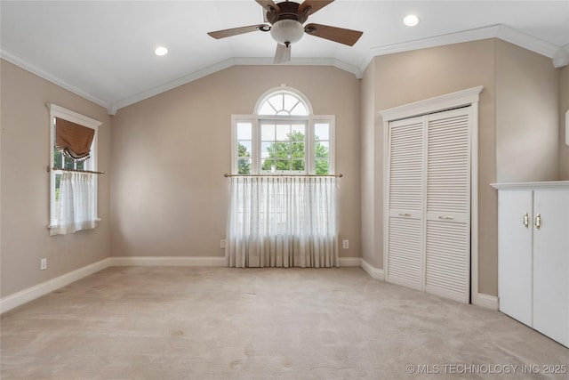 unfurnished bedroom with ornamental molding, light colored carpet, a closet, baseboards, and lofted ceiling