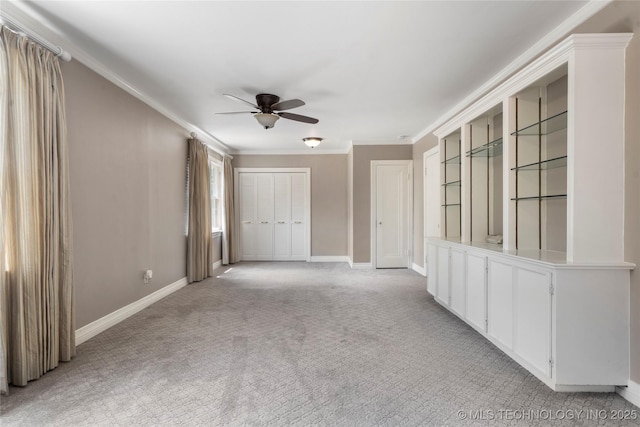 empty room with ceiling fan, baseboards, ornamental molding, and light carpet