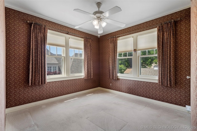 carpeted spare room featuring wallpapered walls, baseboards, a ceiling fan, and ornamental molding