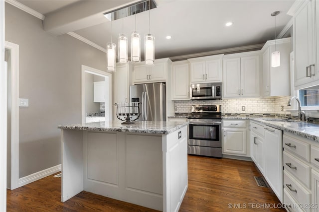 kitchen with appliances with stainless steel finishes, a sink, tasteful backsplash, a kitchen island, and white cabinetry