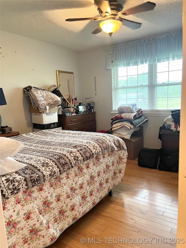 bedroom featuring wood finished floors, a textured ceiling, and ceiling fan