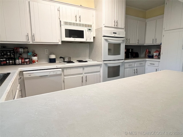 kitchen with white appliances, light countertops, and white cabinetry