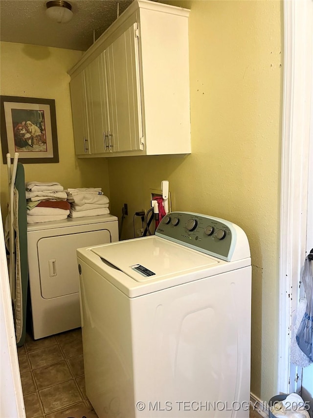 laundry room featuring cabinet space, washing machine and dryer, and dark tile patterned floors