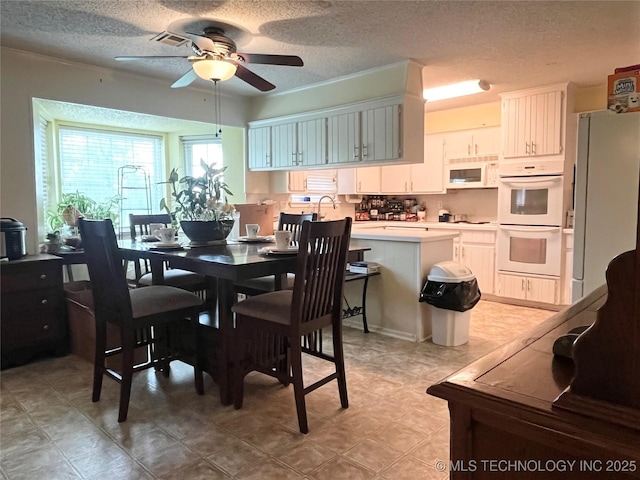 dining area featuring ceiling fan and a textured ceiling