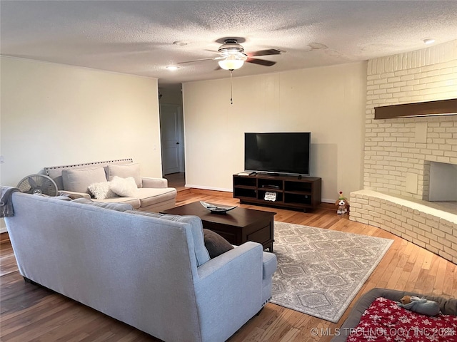 living area featuring a ceiling fan, wood-type flooring, a textured ceiling, and baseboards