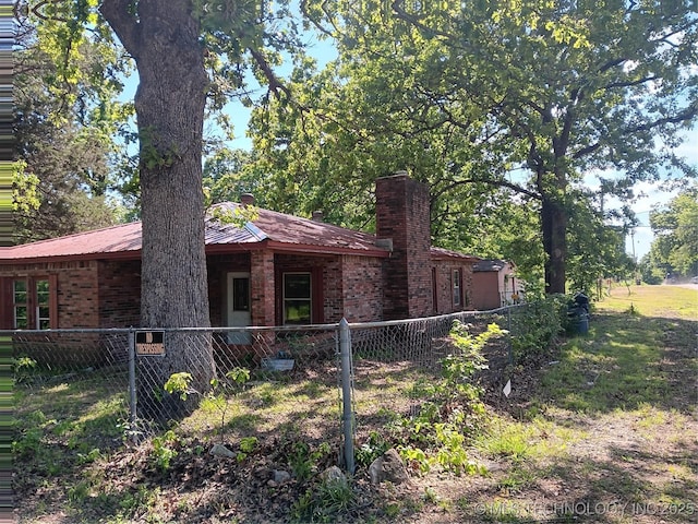 130 E Cherokee Ave N, Spavinaw, OK 74366 - view of home's exterior featuring brick siding, a fenced front yard, and a chimney