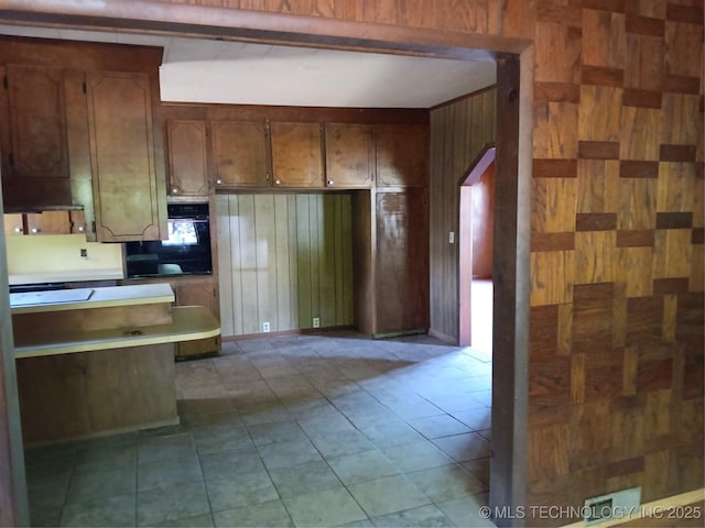 130 E Cherokee Ave N, Spavinaw, OK 74366 - kitchen featuring black oven, wooden walls, tile patterned flooring, and brown cabinets