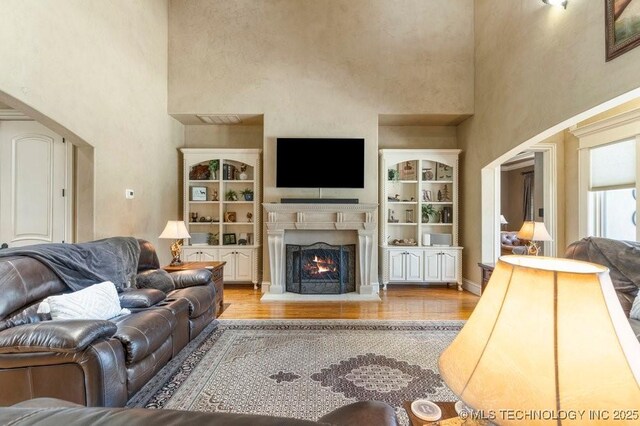 716 W 108th Pl S, Jenks, OK 74037 - living room featuring a high ceiling, wood finished floors, and a lit fireplace