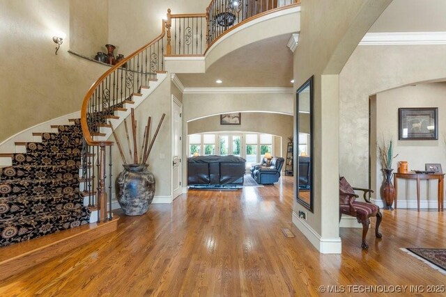 716 W 108th Pl S, Jenks, OK 74037 - foyer entrance featuring a towering ceiling, wood finished floors, stairs, ornamental molding, and arched walkways