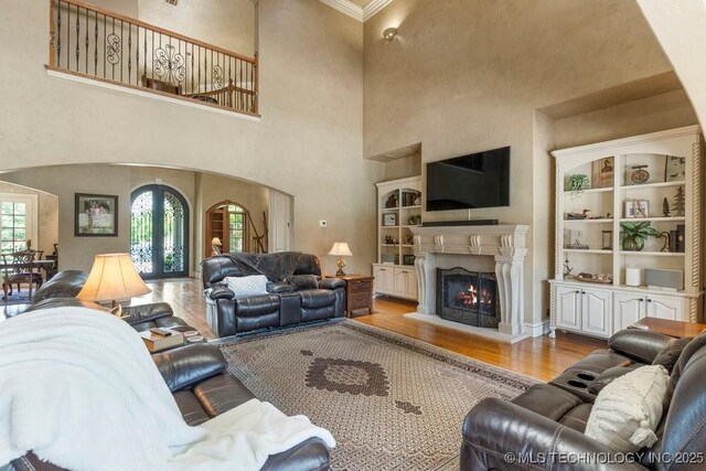 716 W 108th Pl S, Jenks, OK 74037 - living room featuring arched walkways, wood finished floors, french doors, a lit fireplace, and ornamental molding